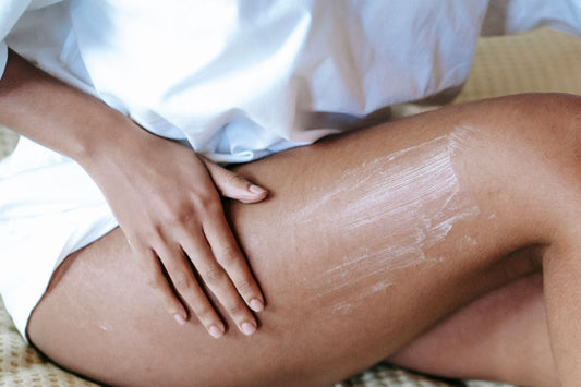 Woman applying body lotion to her thigh, illustrating daily skincare and moisturizing for soft, hydrated skin.